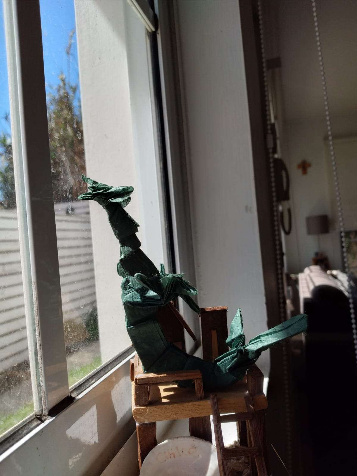 an origami piece of a green dragon looking out of a window