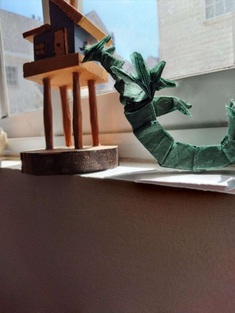 an origami piece of a green dragon from a low angle